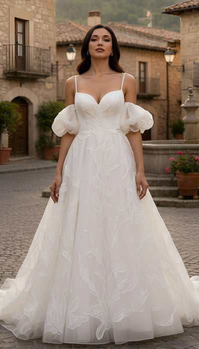 Woman wearing a white wedding dress with puffed sleeves in an outdoor setting.