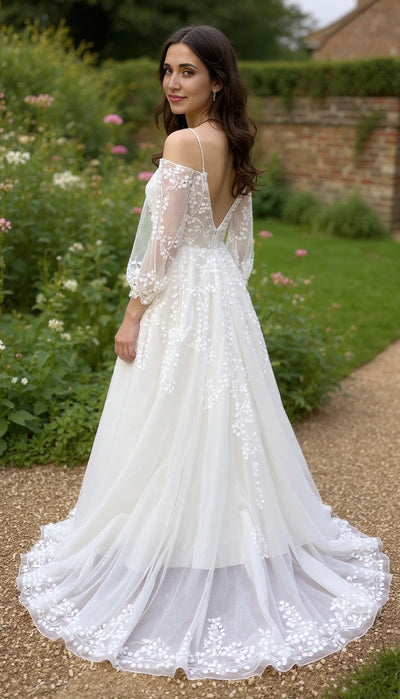 Woman in a white lace wedding dress standing in a garden.
